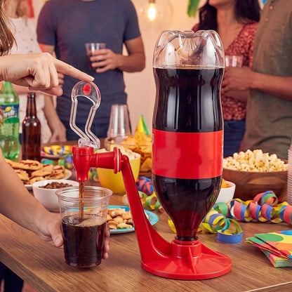 A person's hand presses the lever of a red and clear plastic beverage dispenser, pouring soda into a cup.