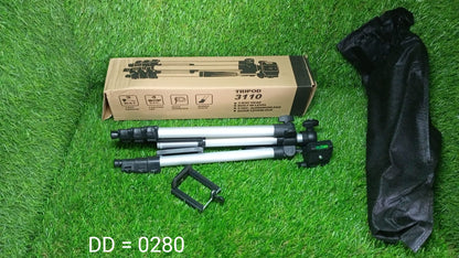 A silver and black tripod, its carrying bag, and its cardboard box are laid out on a vibrant green grassy surface.