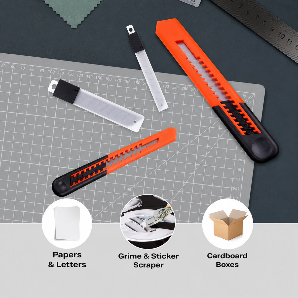 Two orange utility knives and blade cases on a grey cutting mat, with icons showing uses for paper, grime, and boxes.