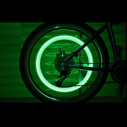 A bicycle wheel with a bright green glowing ring, viewed from the side in a dark setting.