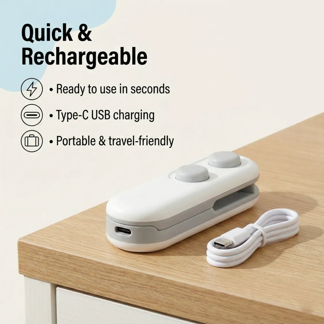The white and grey bag sealer and cutter is on a wooden surface next to its coiled white USB-C charging cable.