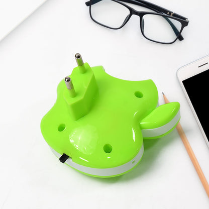 The back of the green apple-shaped LED night light with its two-pronged plug, next to glasses and a phone.