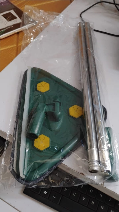 The green triangle mop head and its silver handle are packaged in clear plastic, resting on a white surface next to a
