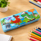 Blue pencil case with cartoon dinosaurs, a built-in sharpener, and a small plant in the background.