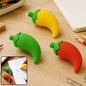 Three chili pepper erasers in red, yellow, and green, with a small inset showing a hand using a yellow eraser on paper.