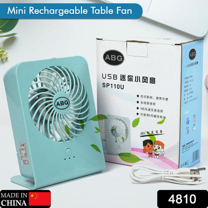 A mint green portable desk fan next to its white and brown product box, with a white USB cable.