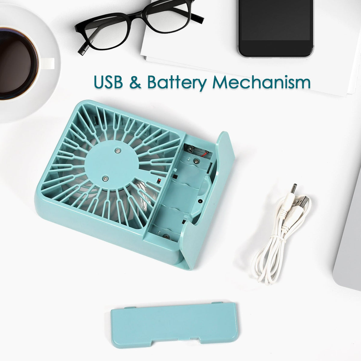 An overhead view of a mint green portable desk fan with its battery compartment open, next to a white USB cable.