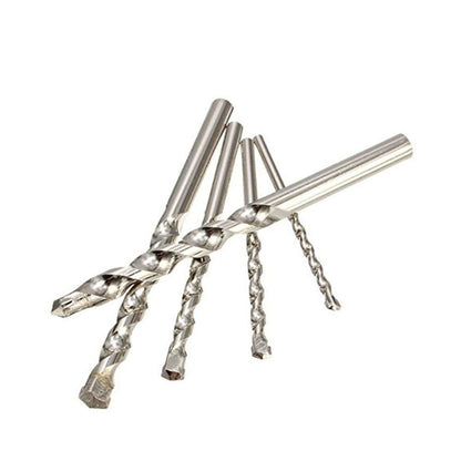 Five silver masonry drill bits of varying sizes are scattered on a white background.
