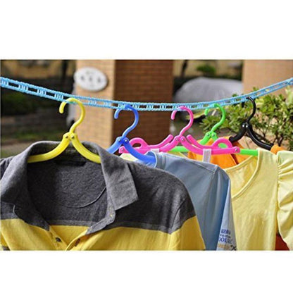 Colorful plastic hangers with clothing are hanging on a blue clothesline outdoors.