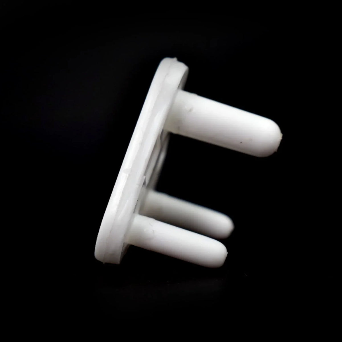 A white 3-pin socket cover is angled against a black background, highlighting its smooth plastic texture.