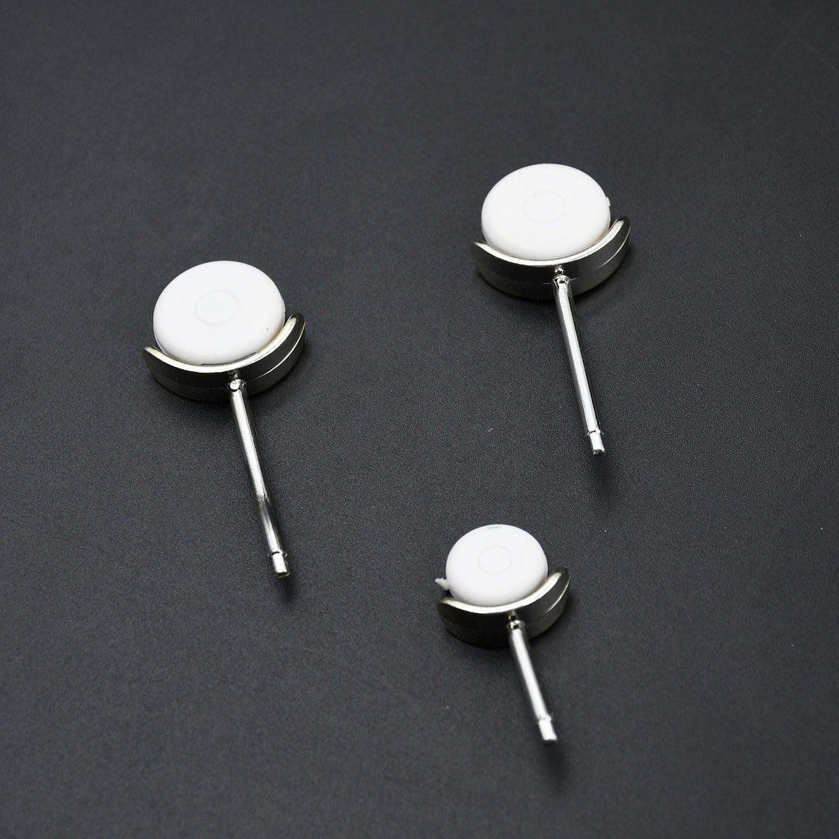 Three small white and silver wheels, designed to attach to the airplane fan, are arranged on a dark surface.
