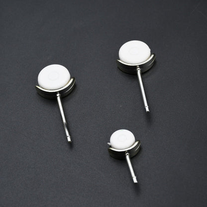 Three small white and silver wheels, designed to attach to the airplane fan, are arranged on a dark surface.