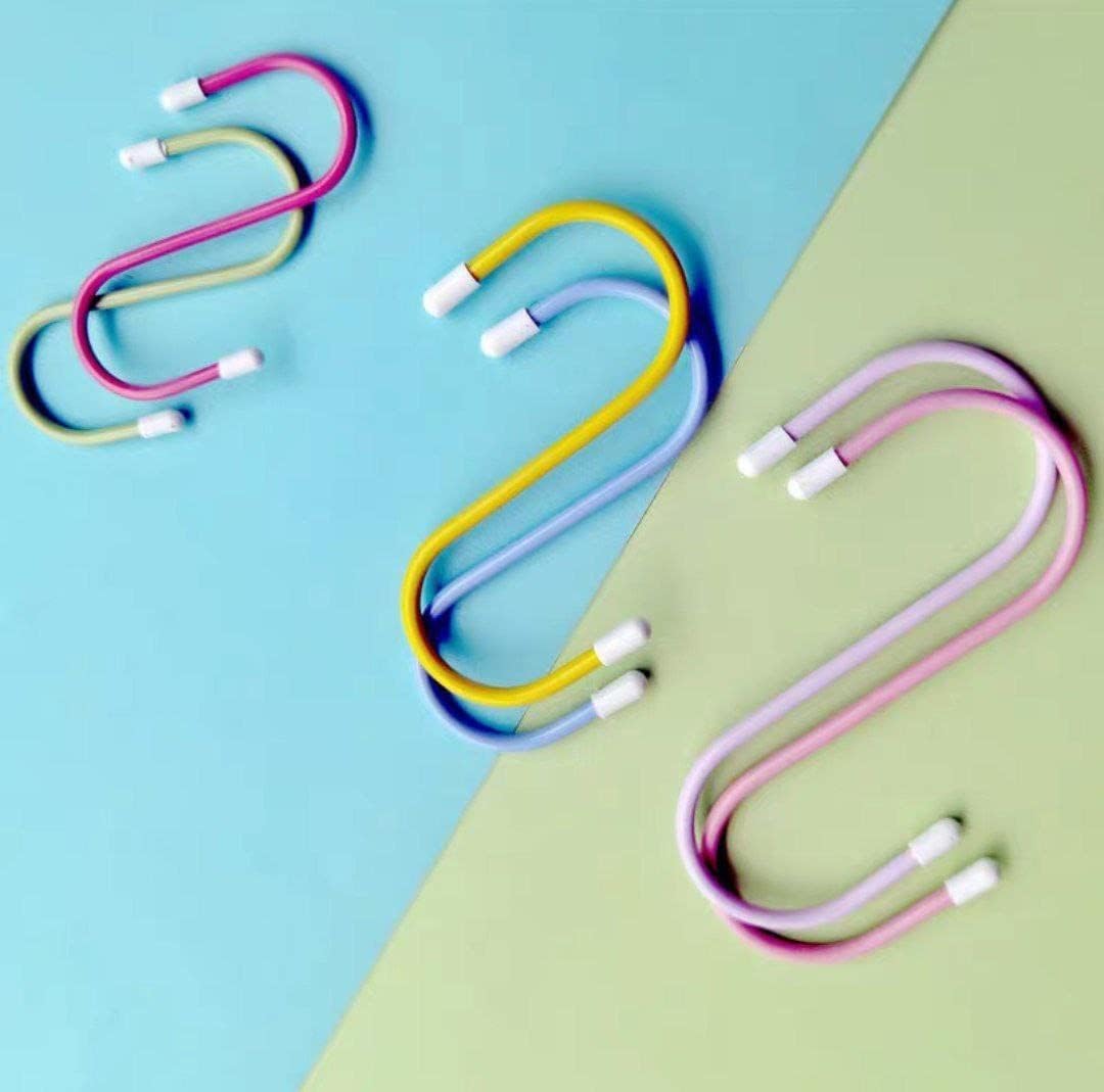 Six colorful plastic coated S hooks in yellow, blue, pink, and purple, arranged on a blue and green background.