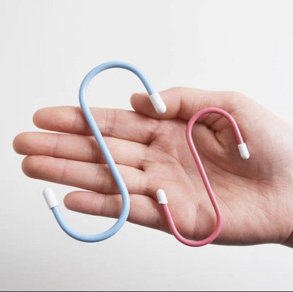 A hand holding a blue and a pink plastic coated S hook, showing their size.