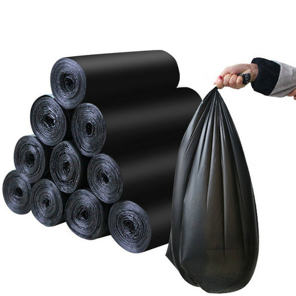 A hand holds up a full black garbage bag next to a stack of rolled black garbage bags.