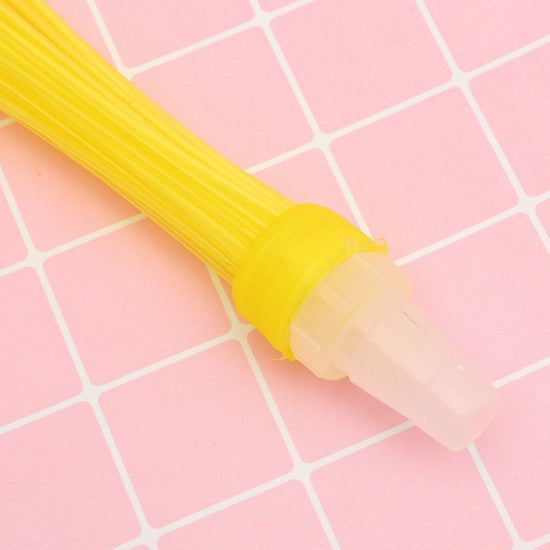 Close-up of a yellow water balloon nozzle with a clear plastic adapter on a pink grid background.