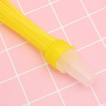 Close-up of a yellow water balloon nozzle with a clear plastic adapter on a pink grid background.