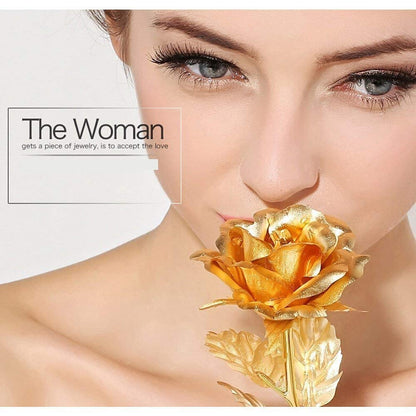 A woman's face is shown close-up, with a gold-plated rose held near her nose.