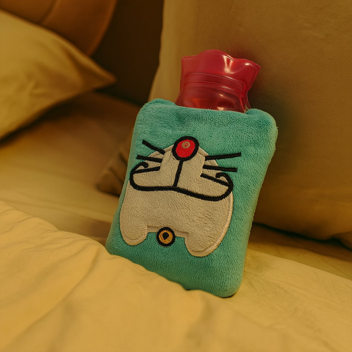 A light blue hot water bag with a Doraemon face design rests on yellow bedding.
