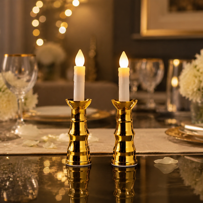 Two gold-based LED candles illuminate a dining table set with wine glasses and white flowers.