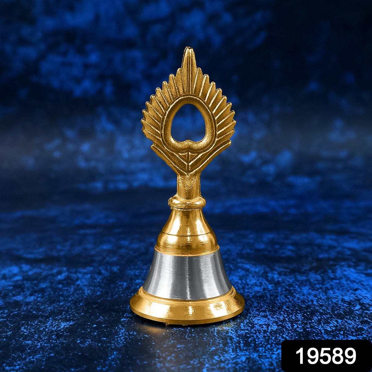 A small brass and steel pooja bell with a peacock feather design stands against a textured dark blue background.