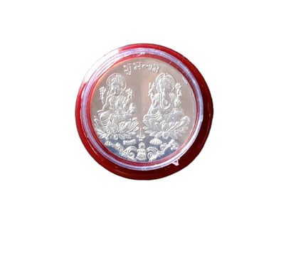 A silver coin with Lakshmi and Ganesha in a red and clear plastic case, isolated on a white background.