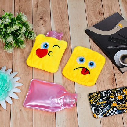 Two yellow emoji hot water bags and one pink plastic hot water bottle are on a light surface.