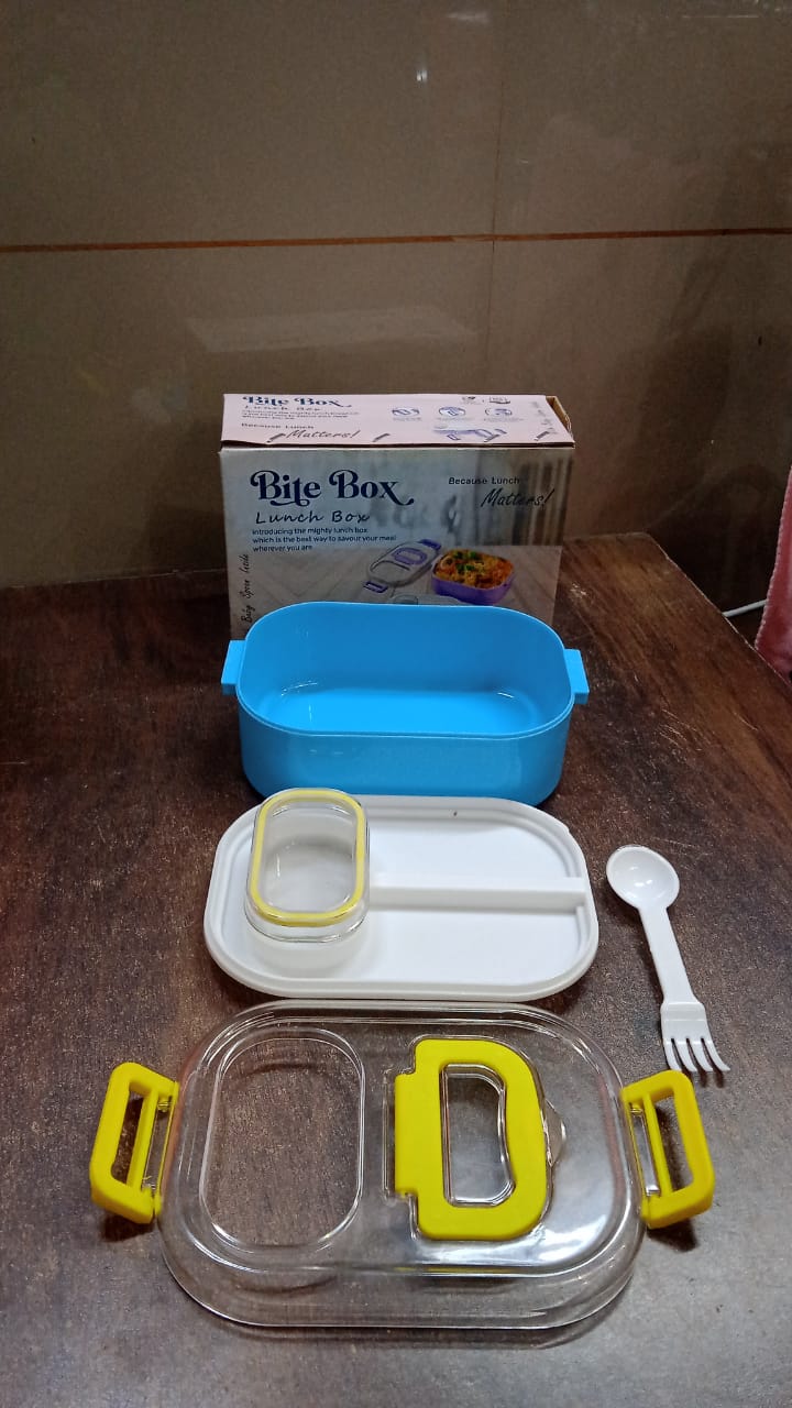 The lunch box components, including the box, lid, divider, and small container, are laid out on a wooden table next to its