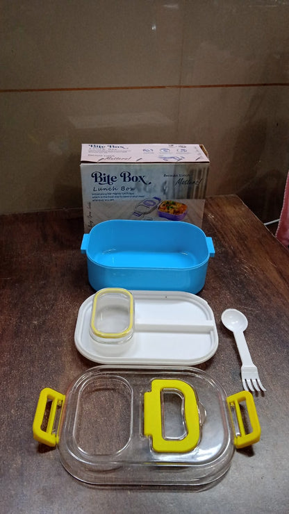 The lunch box components, including the box, lid, divider, and small container, are laid out on a wooden table next to its