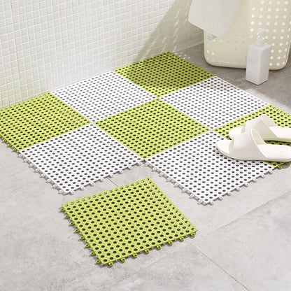 A green and white checkerboard anti-slip mat on a tiled floor with a single green mat tile and white slippers.