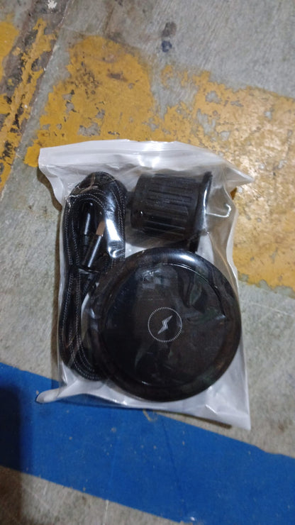 The black magnetic wireless car charger, air vent mount, and USB-C cable sealed in clear plastic packaging on a concrete