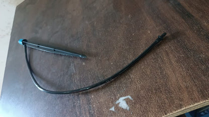 A black and blue water dripper with a thin black hose lying on a dark brown wooden surface.