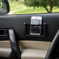 A black mesh car organizer holding a white smartphone, attached to a car door panel.