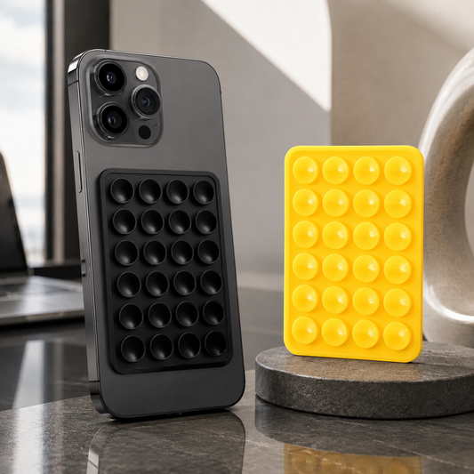A black silicone suction phone holder attached to a grey phone, next to a yellow one on a stone pedestal.