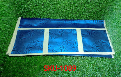 A dark blue refrigerator top cover with a subtle floral pattern and light yellow trim, folded on green artificial grass.