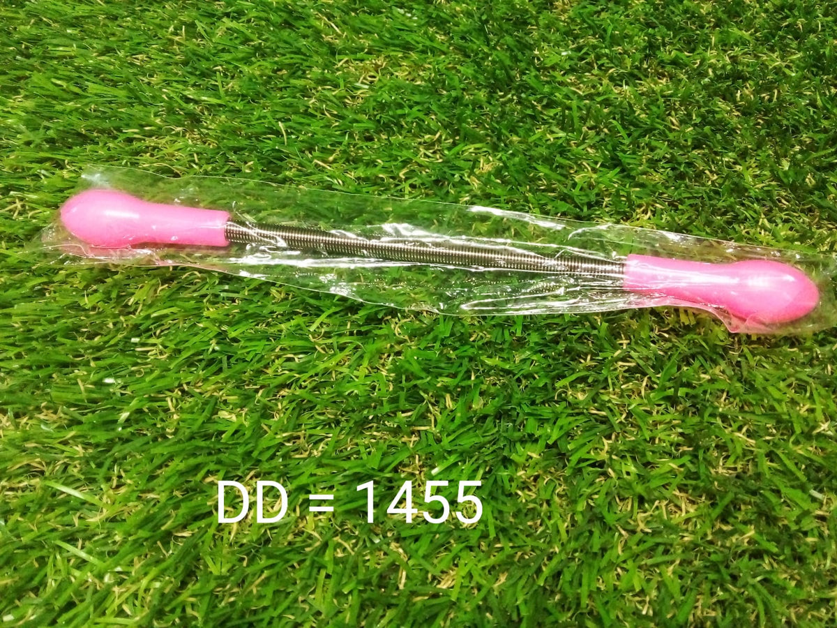 A pink and silver facial hair remover spring tool in clear plastic packaging on a green grass-like surface with text 'DD =