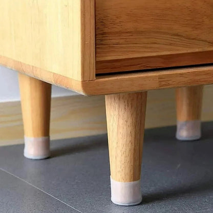 Three light wooden furniture legs with translucent silicone protectors on a gray tiled floor.