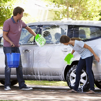 A man and a child wash a silver car with bright green microfiber gloves, surrounded by soap suds.