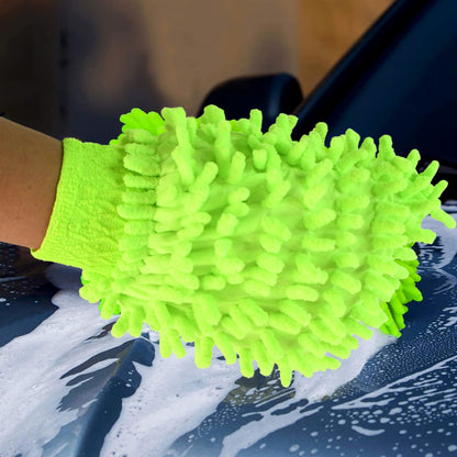 A hand in a bright green microfiber glove washes the hood of a dark blue car, covered in white suds.