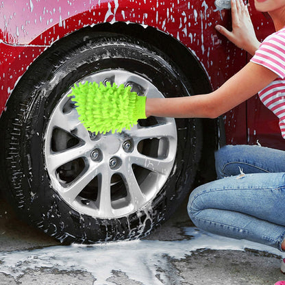 A person in jeans and a striped shirt washes a red car's wheel with a bright green microfiber glove.