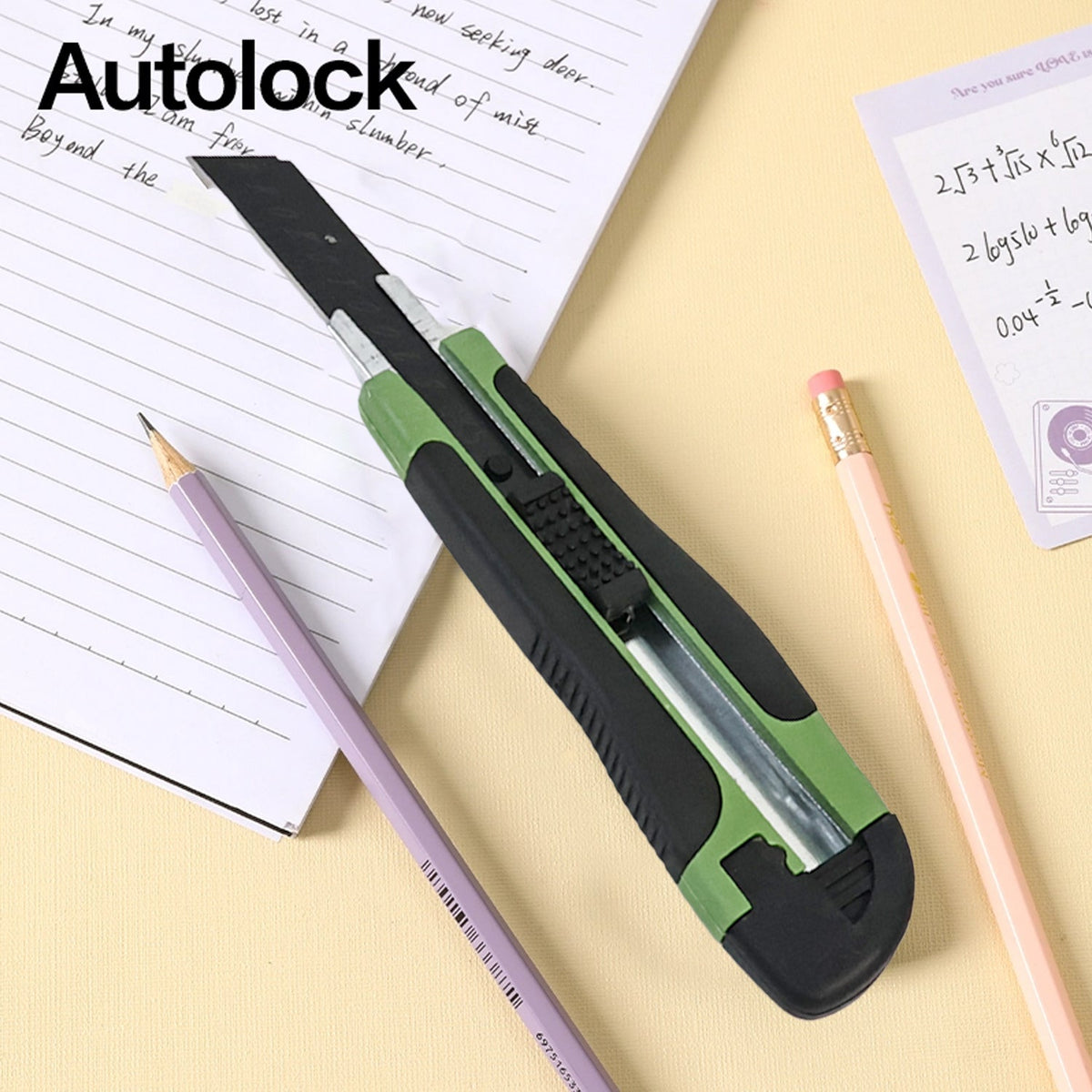 A green and black utility knife with the word "Autolock" on a notebook with pencils.