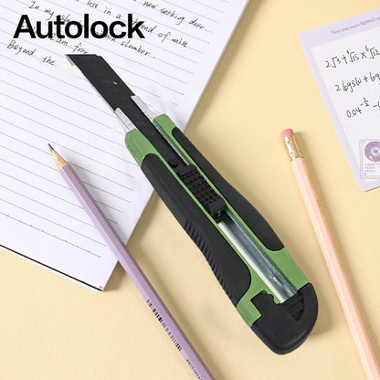 A green and black utility knife with the word "Autolock" on a notebook with pencils.