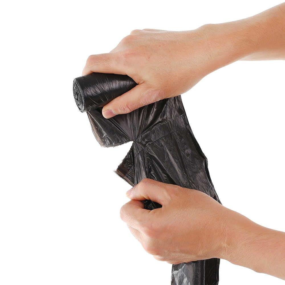 Hands tearing a black garbage bag from a roll, showing the perforated edge.