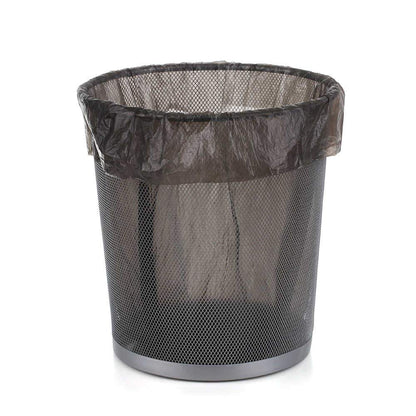 A black mesh wastebasket with a black garbage bag lining the inside, on a white background.