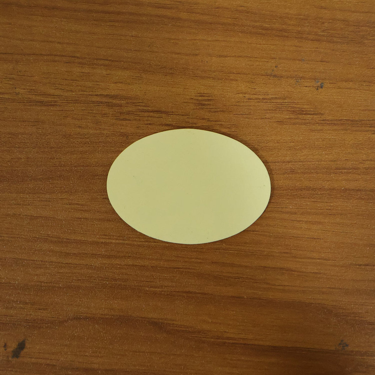 A single light yellow oval pad resting on a textured brown wooden surface.