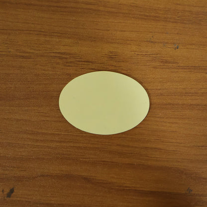 A single light yellow oval pad resting on a textured brown wooden surface.
