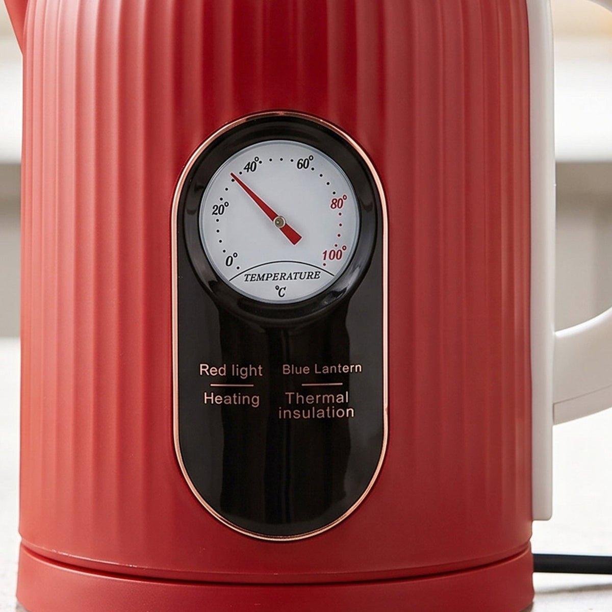 A close-up of the red ribbed electric kettle shows a circular temperature gauge and indicator lights for heating and thermal