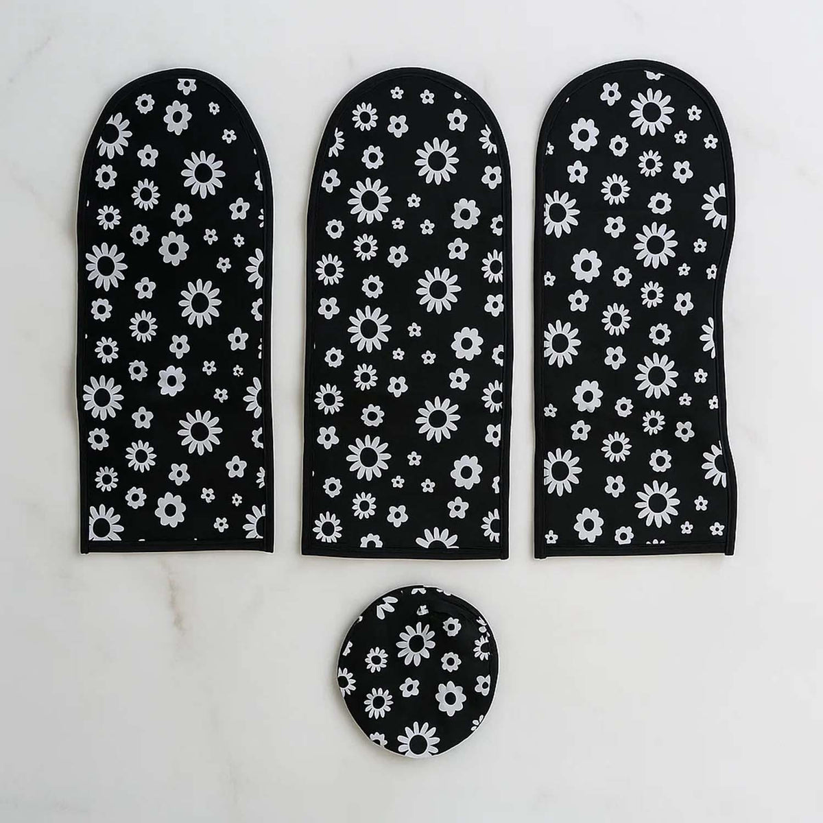 Three long black and white floral dust covers and one round cover arranged on a white marble surface.