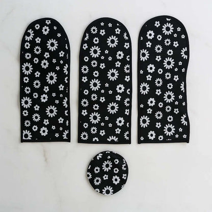 Three long black and white floral dust covers and one round cover arranged on a white marble surface.