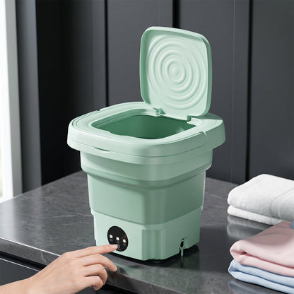 A green portable washing machine with its lid open, showing the ribbed interior, stands against a plain white background.